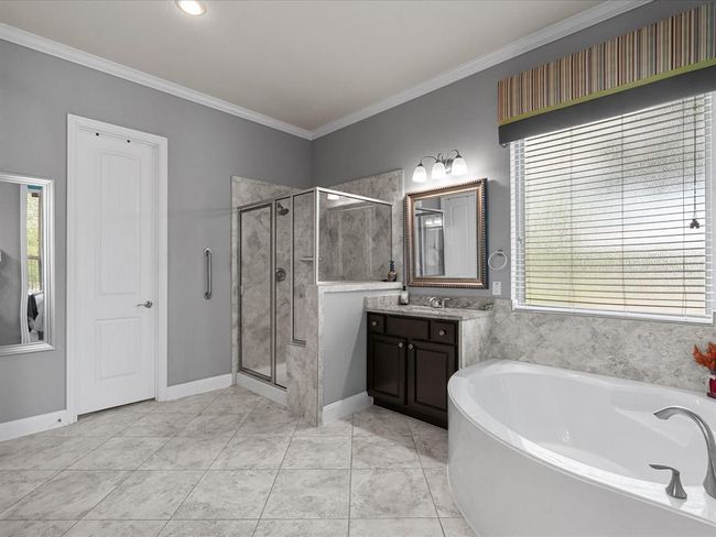 This is a spacious, open-concept living area with a modern kitchen in the background. It features a cozy fireplace, ceiling fan, and stylish decor, creating a warm and inviting atmosphere. The room is well-lit with ample natural light, enhancing the elegant design. | Image 15