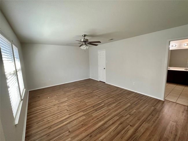 Spare room featuring dark wood-type flooring, baseboards, ceiling fan, and visible vents | Image 12