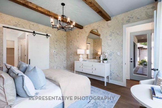 Bedroom featuring dark wood-style flooring, beamed ceiling, a chandelier, a barn door, and wallpapered walls | Image 13