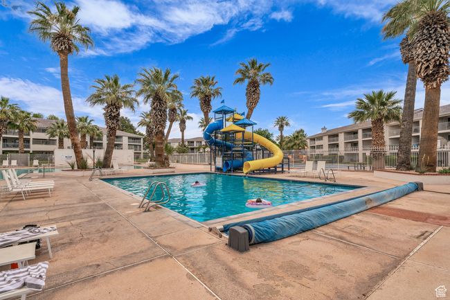 Community pool with a water slide and a patio | Image 15