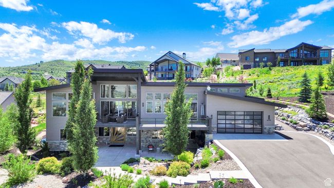 Contemporary home featuring stone siding, driveway, a patio area, a garage, and a balcony | Image 97