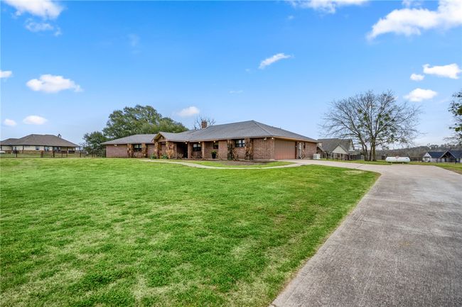 View of front of property with a garage, concrete driveway, fence, a front lawn, and brick siding | Image 5