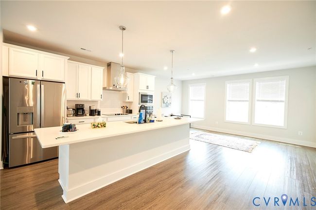 Kitchen with appliances with stainless steel finishes, an island with sink, wall chimney range hood, wood finished floors, and recessed lighting | Image 36