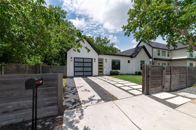 Modern farmhouse style home with driveway, a gate, a garage, and board and batten siding | Image 4
