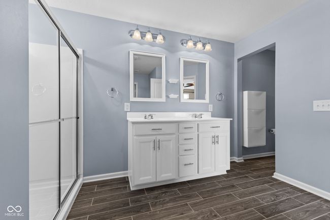 Master bathroom featuring wood finish floors, double vanity, and a stall shower | Image 17