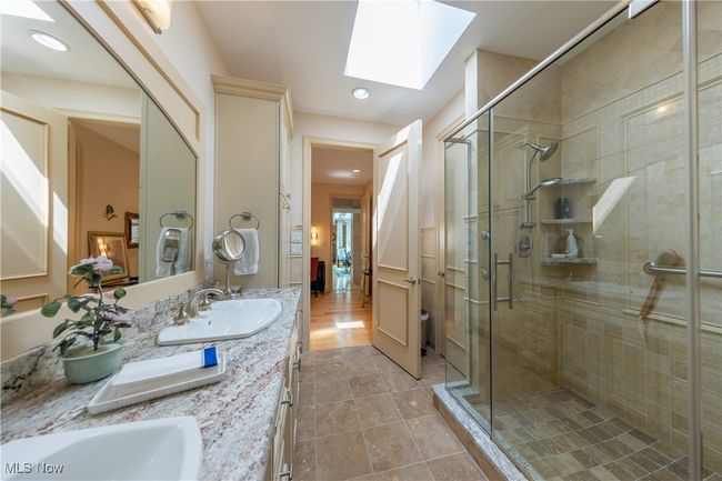 Primary bath with a skylight, a shower stall, double vanity, and a sink | Image 33