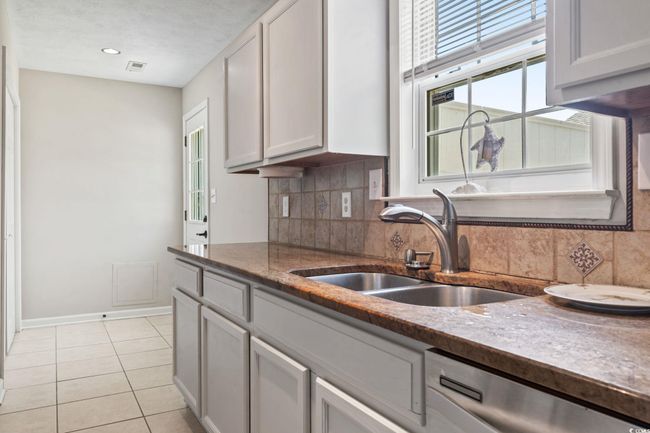 Kitchen with stainless steel dishwasher, tasteful backsplash, light tile patterned flooring, and stone countertops | Image 14