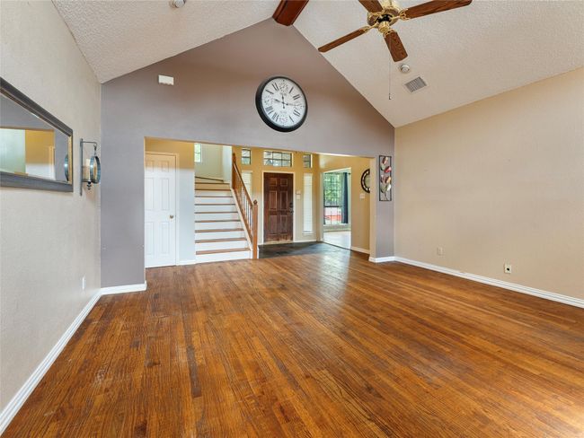 Unfurnished living room with high vaulted ceiling, stairway, ceiling fan, beamed ceiling, and wood finished floors | Image 5