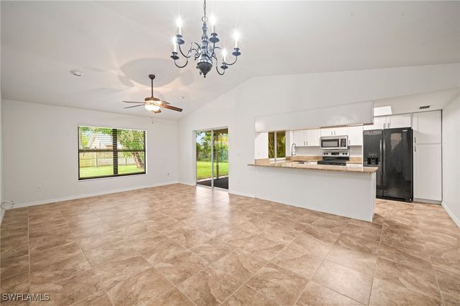 Unfurnished living room featuring vaulted ceiling, a chandelier, and a ceiling fan | Image 6
