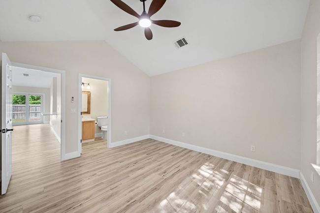Unfurnished bedroom with vaulted ceiling, light wood-style floors, ensuite bathroom, and ceiling fan | Image 28