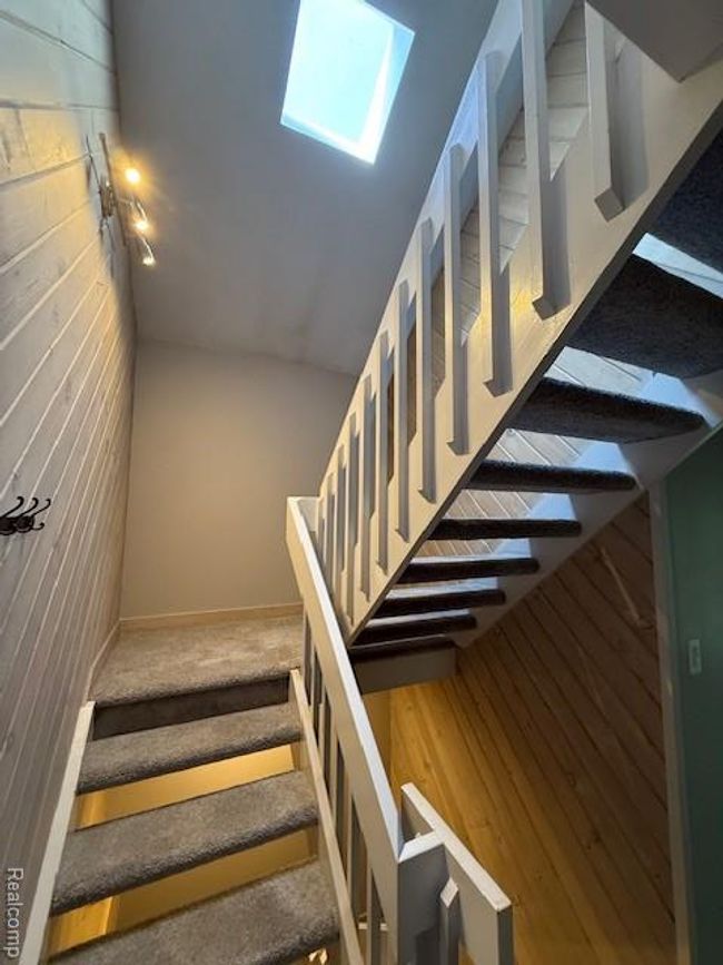 Staircase featuring a skylight and wood walls | Image 19