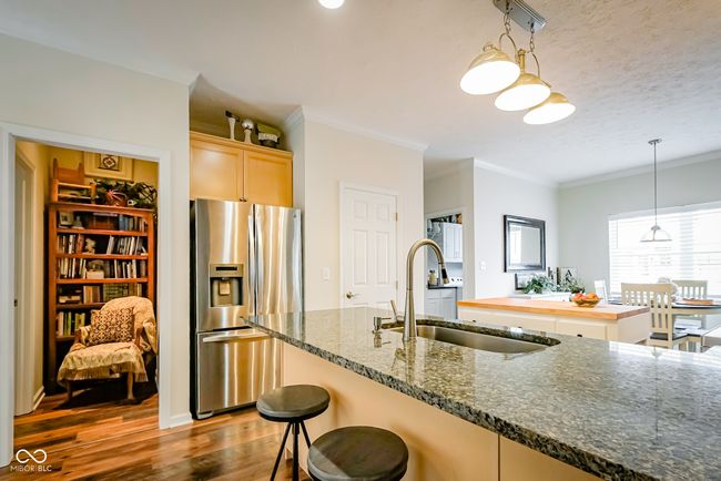 kitchen featuring stainless steel refrigerator with ice dispenser, a sink, wood finished floors, ornamental molding, and hanging light fixtures | Image 10