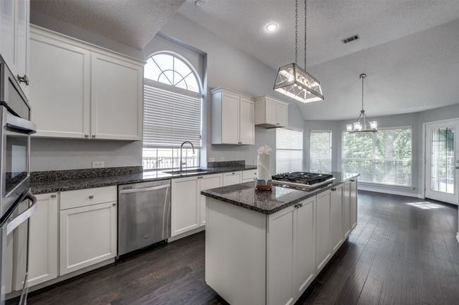 Kitchen featuring a sink, a kitchen island, a chandelier, a textured ceiling, and appliances with stainless steel finishes | Image 10