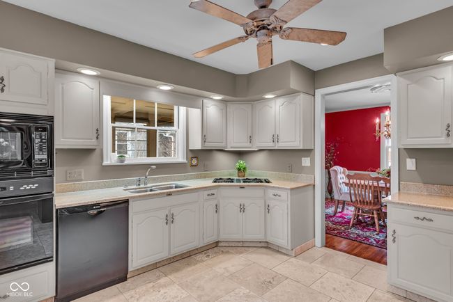 kitchen featuring light countertops, ceiling fan, white cabinetry, a sink, and black appliances | Image 13