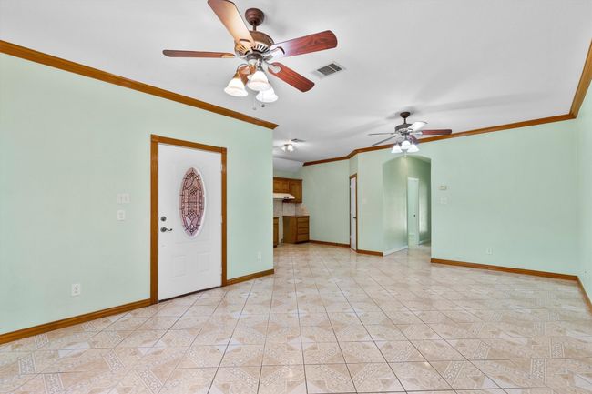 Unfurnished living room featuring a ceiling fan, crown molding, baseboards, and light tile patterned floors | Image 17