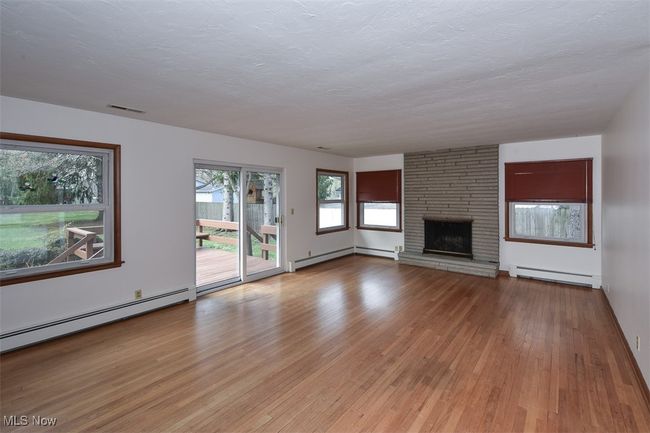 Unfurnished living room featuring a baseboard heating unit, visible vents, light wood-style floors, and a baseboard radiator | Image 15