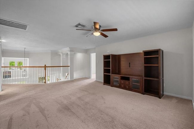 This spacious game room features neutral carpeting, a ceiling fan, and a large window with a view of the deck and lake. | Image 23