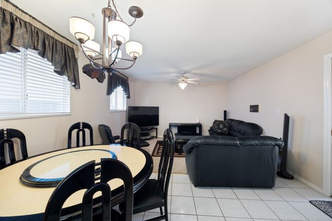 Dining area with light tile patterned floors and ceiling fan with notable chandelier | Image 16
