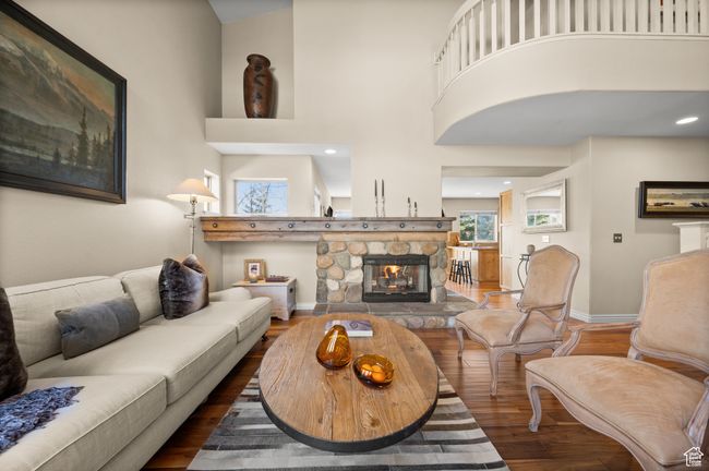 Living area with a stone fireplace, wood finished floors, and a high ceiling | Image 4