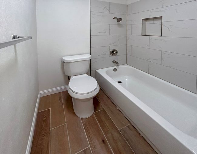 Primary bathroom with toilet, tiled shower / bath combo, and Luxury Vinyl Plank flooring | Image 21