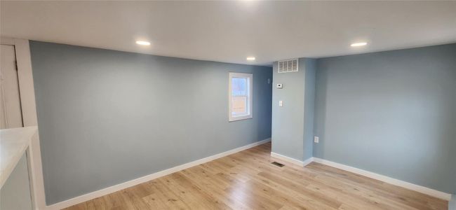 Empty room with light wood finished floors, baseboards, visible vents, and recessed lighting | Image 13