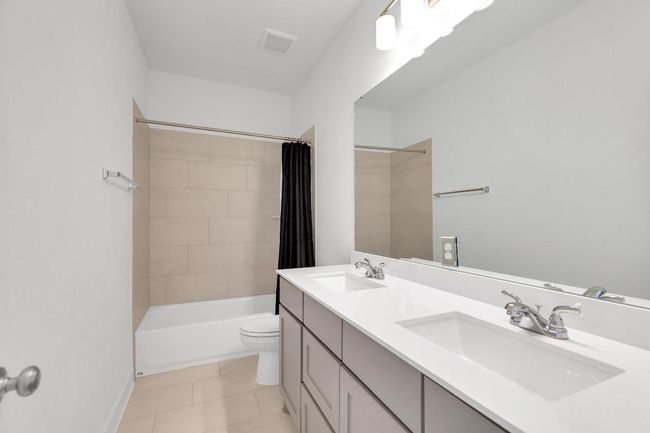 Bathroom featuring double vanity, shower / bath combination with curtain, and tile patterned floors | Image 33