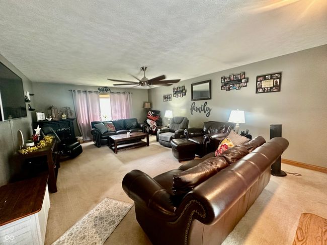 carpeted living area with a textured ceiling and a ceiling fan | Image 21