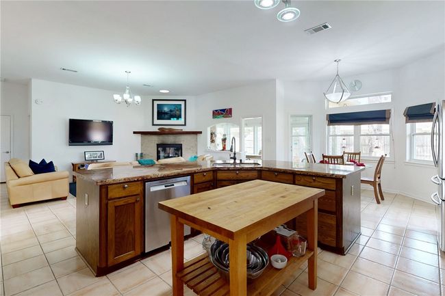 Kitchen with a sink, open floor plan, light tile patterned flooring, dishwasher, and visible vents | Image 13