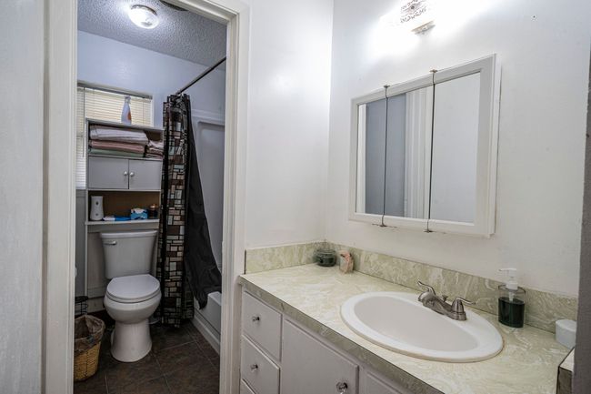 Bathroom with vanity, tile patterned floors, a textured ceiling, and shower / bath combo | Image 20