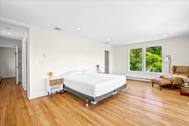 Bedroom with a baseboard radiator, light wood-type flooring, recessed lighting, and baseboards | Image 27