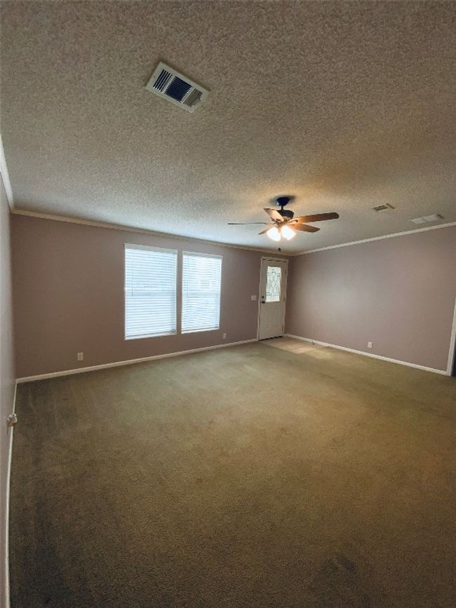 Empty room featuring a textured ceiling, visible vents, baseboards, and light colored carpet | Image 11