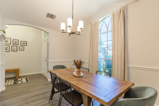 Dining space with vaulted ceiling, arched walkways, a chandelier, wood finished floors, and baseboards | Image 7