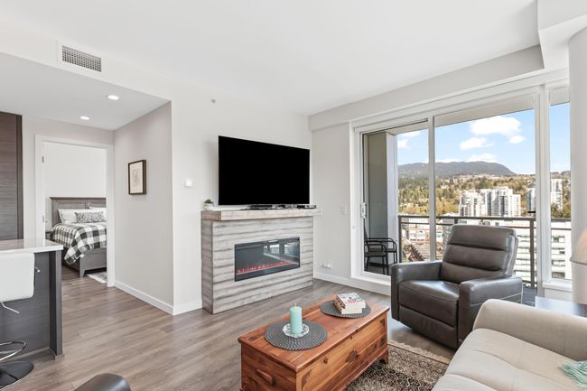 Living area with recessed lighting, wood finished floors, visible vents, baseboards, and a glass covered fireplace | Image 11
