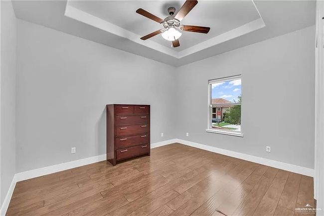 Spare room with a tray ceiling, a ceiling fan, and wood finished floors | Image 10