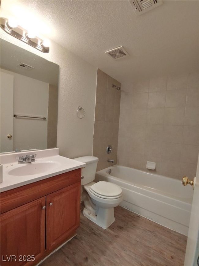Full bathroom with toilet, a textured ceiling, vanity, hardwood / wood-style floors, and tiled shower / bath combo | Image 11