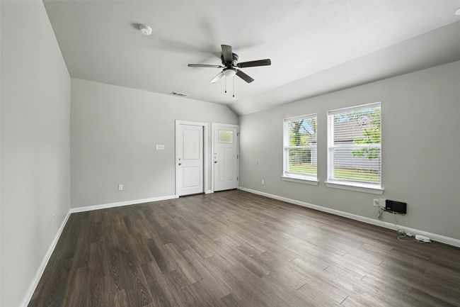 Empty room featuring dark wood finished floors, vaulted ceiling, and a ceiling fan | Image 8