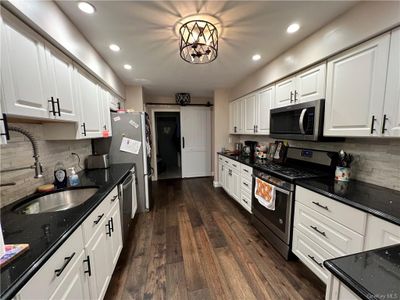 Kitchen featuring appliances with stainless steel finishes, dark hardwood / wood-style floors, white cabinets, and a barn door | Image 2