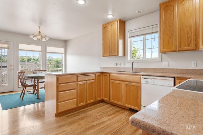 Kitchen with white appliances, healthy amount of natural light, a peninsula, a chandelier, and recessed lighting | Image 9