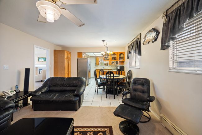 Living area with light tile patterned flooring, baseboard heating, light carpet, and ceiling fan with notable chandelier | Image 19