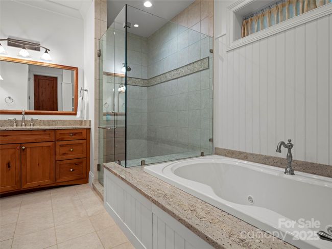 Terrace level second primary suite featurs double granite vanities, jetted tub with granite surround, frameless glass door shower and separate water closet, as well as a linen closet. | Image 32