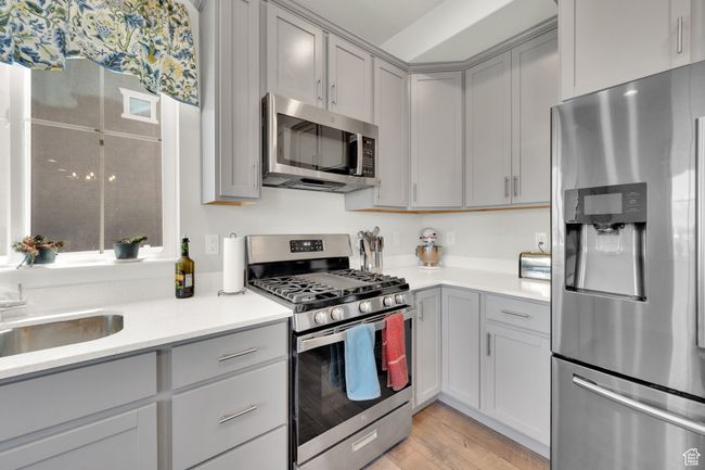 Kitchen featuring stainless steel appliances, gray cabinetry, light countertops, and light wood finished floors | Image 9