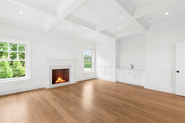 Living room featuring beamed ceiling, light wood-style floors, coffered ceiling, a decorative wall, and a high end fireplace | Image 40