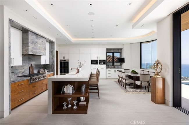 The open-concept, gourmet kitchen impresses with premium Dacor appliances, Miele built-in coffee station, walk-in pantry, and oversized porcelain and quartzite island, ideal for effortless indoor-outdoor entertaining. | Image 12