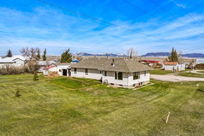 Rear view of property featuring a mountain view, a yard, and roof with shingles | Image 8