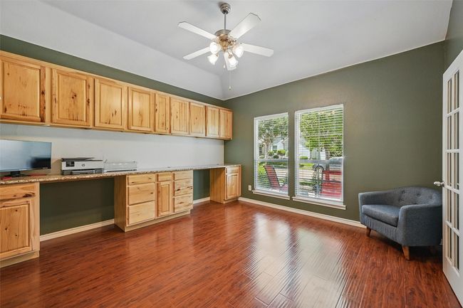 Home office featuring built in desk, dark wood-style flooring, ceiling fan, vaulted ceiling, and baseboards | Image 22
