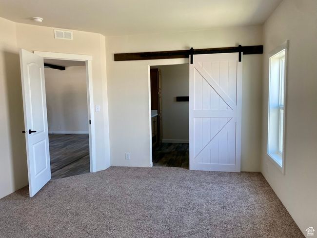 Unfurnished bedroom featuring carpet floors and a barn door | Image 9