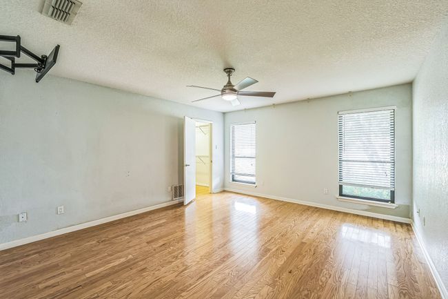Empty room with a wealth of natural light, wood finished floors, ceiling fan, and a textured ceiling | Image 33