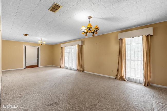Carpeted room featuring a chandelier and baseboards | Image 8