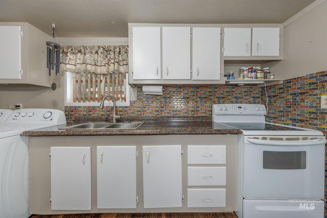 Kitchen featuring white electric range oven, washer / dryer, backsplash, and white cabinets | Image 10
