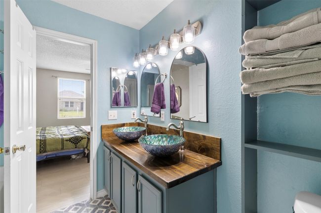 Ensuite bathroom featuring double vanity, a textured ceiling, and wood finished floors | Image 15